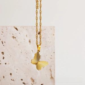 Detailed close-up of 18k gold butterfly pendant with fine brushed radial textures
