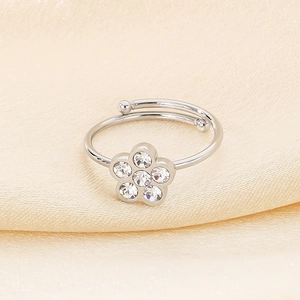 Detailed view of silver flower open ring with sparkling crystals on beige silk fabric