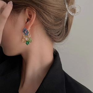 Gros plan de boucles d'oreilles fleurs en cristal coloré portées par un mannequin