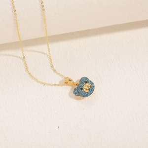 Détail macro du collier plaqué or 14K avec pendentif ours serti de zircons bleus brillants