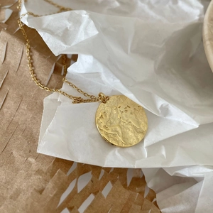 Gold plated 925 silver necklace with embossed world map compass pendant on white paper