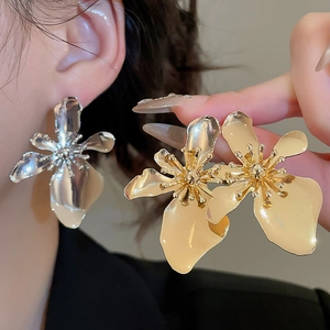 Detailed comparison of gold and silver metallic flower earrings worn by a model