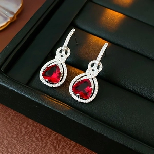 Dettaglio di orecchini a perno in argento con gemme rosse e zirconi scintillanti