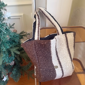 Detail of plush faux fur tote bag with vertical stripes on a chair with Christmas tree