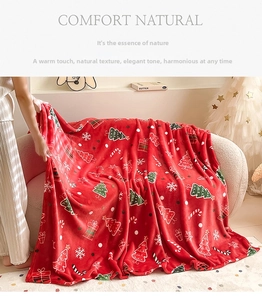 Close-up of soft red flannel Christmas blanket with festive trees and snowflake patterns