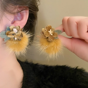 Detailed view of autumn winter plush earrings with brown pom-poms and velvet flowers