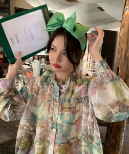 Detail of an oversized green seersucker bow headband styled with a vintage floral shirt