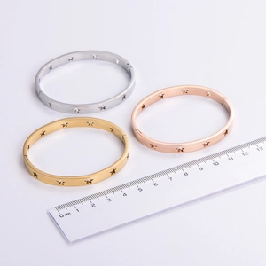 Cut-out star cuff bracelet in gold, silver, and rose gold finishes on a light grey background