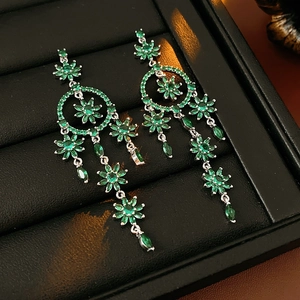 Macro shot of silver tassel earrings with green floral zircons in a black jewelry box