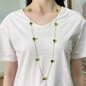 Long gold chain necklace with square green crystal gemstones on model for elegant styling
