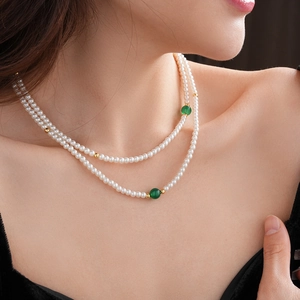 Close-up of double-layered pearl necklace with green beads and gold spacers on model