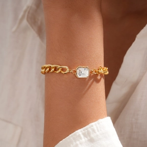 Nahaufnahme des goldenen Kettenarmbands mit rechteckigem Kristall und Pavé-Diamanten