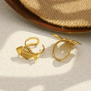 Detailed close-up of 18K gold plated bow and fishbone rings on white stone base