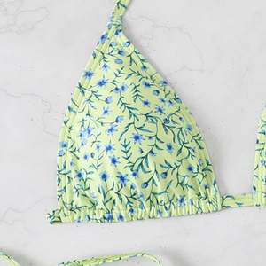 Detail of light green bikini top with blue floral print on marble background