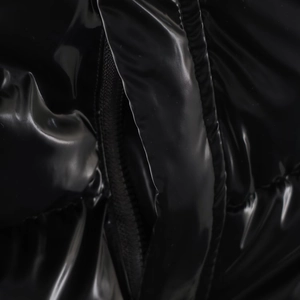 Detailed close-up of glossy waterproof fabric and smooth zipper on black winter jacket
