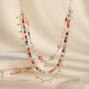 Detail of bohemian layered necklace with colorful beads and floral enamel charms on stone