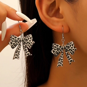 Close-up of acrylic leopard print bow earrings with metallic hooks on a model's ear