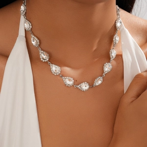 Detail of silver drop-shaped necklace with crystals on model for elegant evening wear