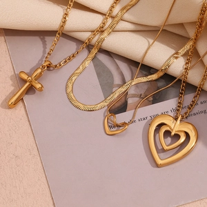 Detail of 18K gold-plated stainless steel cross and heart pendant necklaces with snake chain