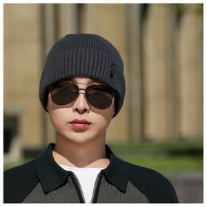 Detail of dark grey knit beanie featuring fine ribbed texture and a side woven label