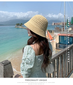 Détail d'un chapeau cloche en paille tressée beige sur fond de plage et mer bleue