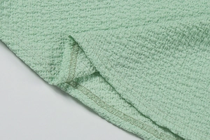 Vue macro du tissu seersucker vert menthe montrant la texture gaufrée et l'ourlet