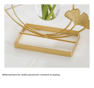 Close-up of golden metal flower vase with ginkgo leaf design and a wide stable base
