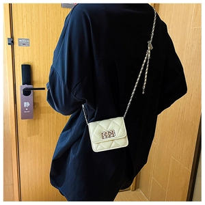 Detail of a quilted crossbody bag in cream PU leather with silver metal chain and clasp