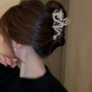 Detail of golden dragon hair claw with rhinestones and red bead on hair