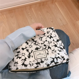 Close-up of black and white floral fabric pouch with Time to Party label and zipper