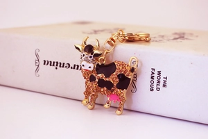 Close-up of golden cow keychain featuring brown rhinestones and enamel details