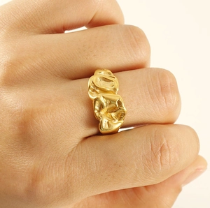 Vue rapprochée de la texture de lave dorée sur la bague en acier portée au doigt
