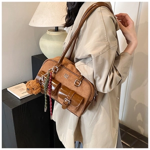 Close-up of brown suede pillow bag with dual leather pockets and cute teddy bear charm