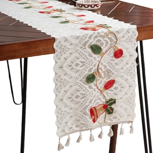 White Christmas lace table runner with bells embroidery and tassels on wooden table