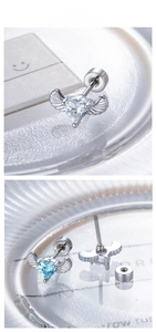 Macro detail of heart-shaped zircon earrings with angel wings and screw-back closure