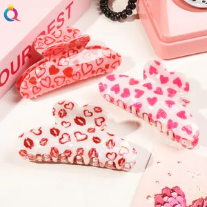Macro shot of acrylic heart and lip print hair claws in vibrant pink and red patterns