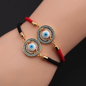 Close-up of adjustable woven evil eye bracelets with blue cubic zirconia in gold settings