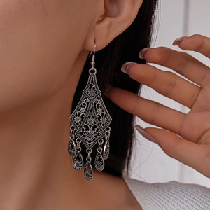 Close-up of vintage silver bohemian drop earrings with hollow flower patterns and tassels