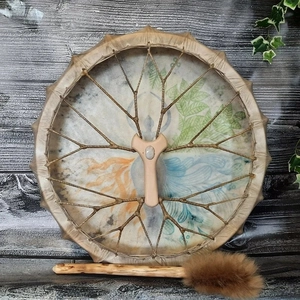 Handmade shamanic drum with goddess pattern and crystal inlay on a rustic wooden background