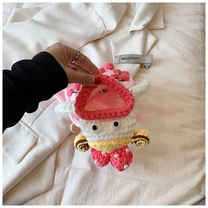 Detail of pink knitted strawberry AirPods case with pearls on a neutral background