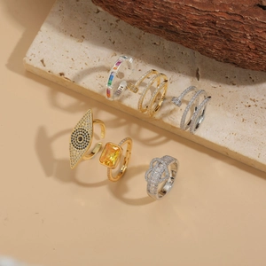 Detail view of assorted gold and silver rings with zircons on a beige stone slab