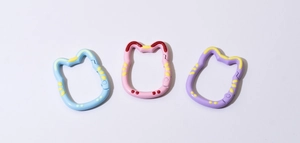 Close-up of cat-shaped spring ring carabiners in blue, pink, and purple colors