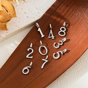 Detailed silver 0-9 number pendants on wood tray for DIY jewelry making