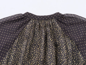 Detail of bohemian ruffle neckline with gold foil dots on sheer pleated chiffon fabric