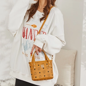 Brown bucket bag with monogram print and golden metal plaque shown on a model