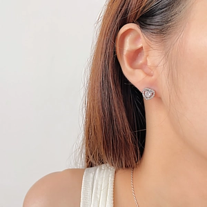 Close-up of heart-shaped stainless steel stud earrings with cubic zirconia on model
