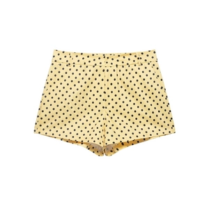 Detail of high-waisted pale yellow shorts with black polka dot print and belt loops