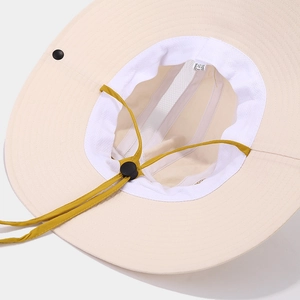 Dettaglio cappello da sole outdoor con tesa beige, cordino giallo e fodera in rete traspirante