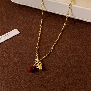 Detail of 18k gold plated necklace featuring a red gourd pendant and small gold bead
