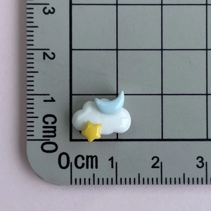 Close-up of mini resin cloud pendant with moon and stars on a centimeter scale ruler